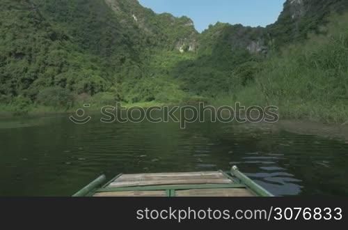 Riding in cave from first-person on boat on the river with scenic views in a sunny day - mountains, green trees and plants. Phong Nha-Ke Bang National Park, Vietnam