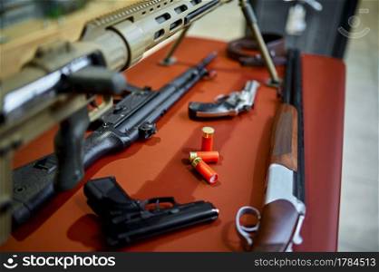 Rifles and pistols on counter in gun store closeup, nobody. Weapon shop interior on background, ammunition assortment, firearms choice, shooting hobby and lifestyle, self protection and security. Rifles and pistols on counter in gun store