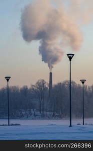 Riga view in winter; Riga, capital city of Latvia in winter time. View of Riga with frozen river Daugava and smoky chimney. City Riga with background of blue sky.