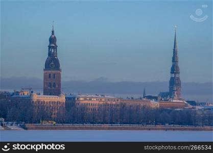 Riga view in winter. Riga, capital city of Latvia in winter time. View of St Peter's Church and St. Jacob's Cathedral. View of Old Riga with frozen river Daugava in the foreground. City Riga with background of blue sky.