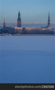 Riga view in winter; Riga, capital city of Latvia in winter time. View of St Peter's Church, St. Jacob's Cathedral and Anglican Church. View of Old Riga with frozen river Daugava in the foreground. City Riga with background of blue sky.