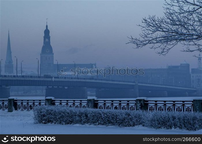 Riga view in winter; Riga, capital city of Latvia in winter time. View of St. Jacob's Cathedral and Riga Dome Cathedral. View of Old Riga with frozen river Daugava in the foreground. City Riga with background of blue sky.