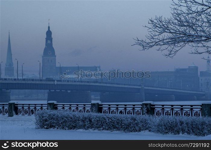 Riga view in winter  Riga, capital city of Latvia in winter time. View of  St. Jacob’s Cathedral and Riga Dome Cathedral. View of Old Riga with frozen river Daugava in the foreground. City Riga with background of blue sky. 
