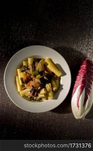 Rigatoni with radicchio served in a white plate on a gray background. Italian pasta with vegetables. Vegan recipe.