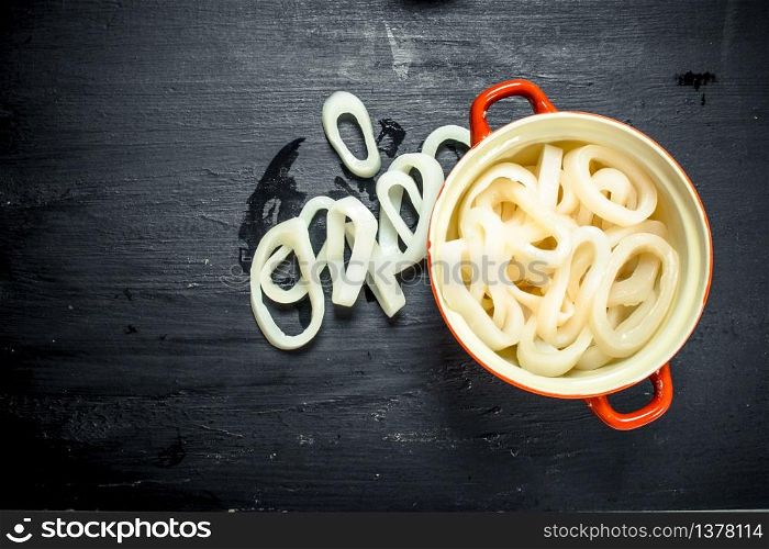Rings of squid in a bowl. On the black chalkboard.. Rings of squid in a bowl.