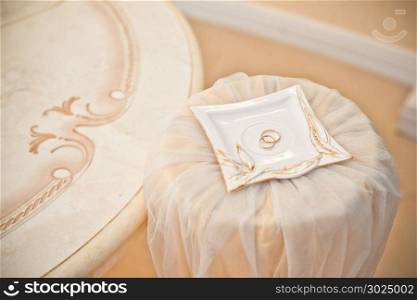 Rings of the newly-married couple at wedding ceremony in a beige hall.