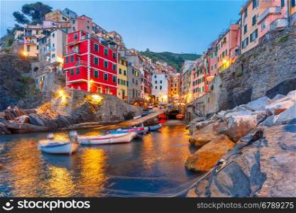 Riomaggiore fishing village during evening twilight blue hour, seascape in Five lands, Cinque Terre National Park, Liguria, Italy.