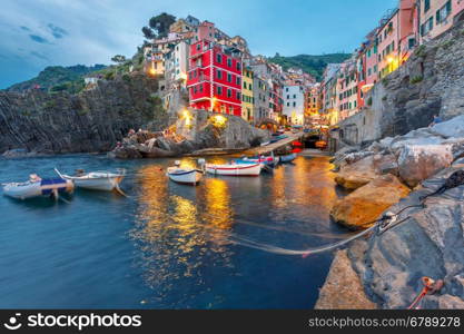 Riomaggiore fishing village during evening twilight blue hour, seascape in Five lands, Cinque Terre National Park, Liguria, Italy.