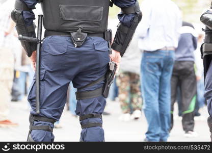 Riot police officer holding hand on his gun during street protest