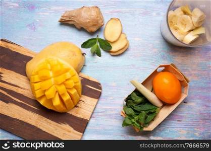 ripe and  fresh yellow mango fruit  with ingredients for smoothie at blue table