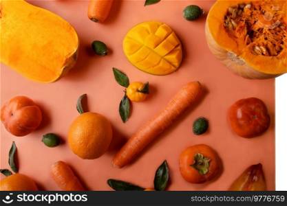 Ripe and tasty orange and yellow fruits, carrots and pumpkin around coral color background. flat lay