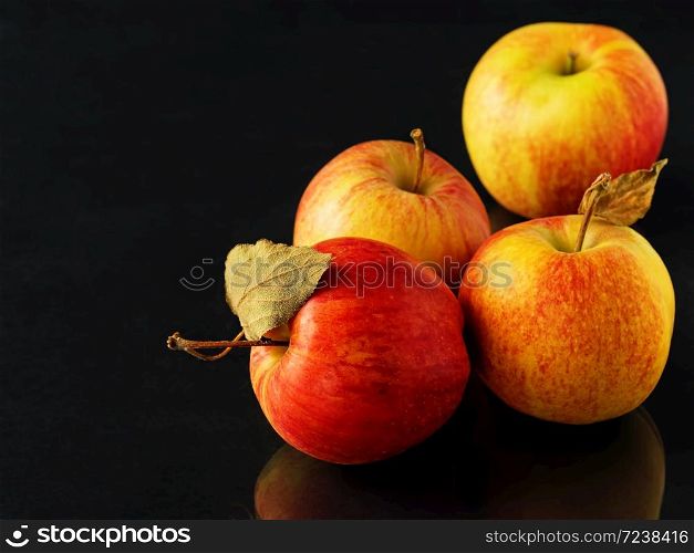 Ripe apples on a black background, close-up, space for text. Autumn harvesting. Reflection of apples on the table