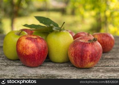 Ripe apples on a wooden table, on green outdoor background. apples