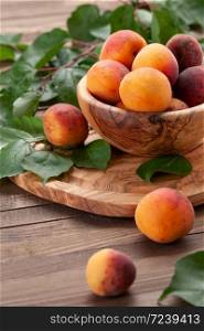 ripe apricots in a wooden bowl on the background of not painted boards close-up