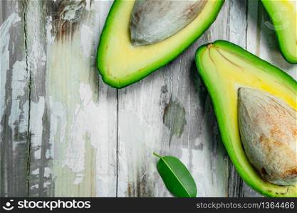 Ripe avocado and pieces of avocado with leaves. On a wooden background.. Ripe avocado and pieces of avocado with leaves.