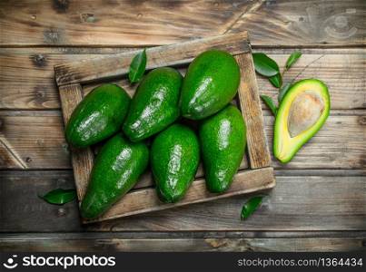 Ripe avocado in a wooden box. On a brown wooden background.. Ripe avocado in a wooden box.