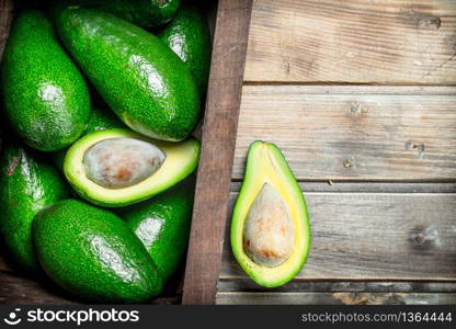 Ripe avocado in a wooden box. On a brown wooden background.. Ripe avocado in a wooden box.