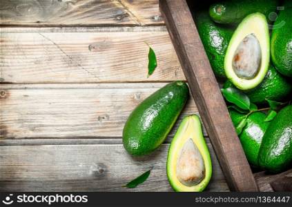 Ripe avocado in a wooden box. On a brown wooden background.. Ripe avocado in a wooden box.