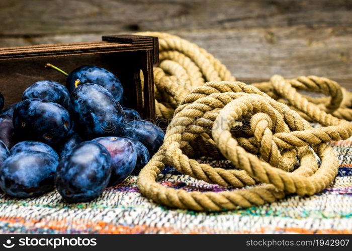 Ripe blue plums in a wooden crate in a rustic composition.. Ripe blue plums in a wooden crate in a rustic composition.