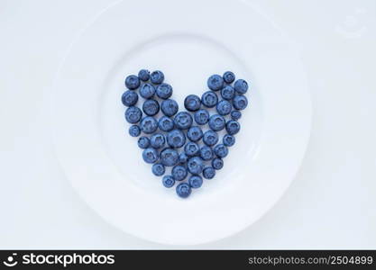 ripe blueberries in a heart shape on a white plate.. ripe blueberries in a heart shape on a white plate