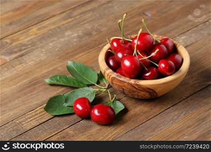 ripe cherries in a wooden bowl on the background of wooden boards
