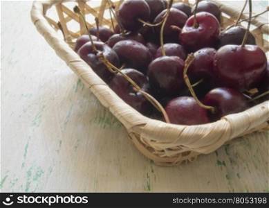 ripe cherries lying in the wicker basket. the fruits of the cherries lying in a wooden basket