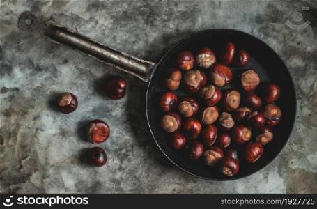 Ripe chestnuts on an old iron pan on the table.. Ripe chestnuts in an old iron pan.