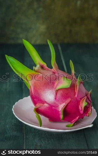 Ripe Dragon fruit on dish over wooden background , still life