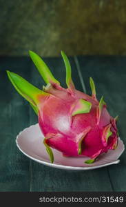 Ripe Dragon fruit on dish over wooden background , still life