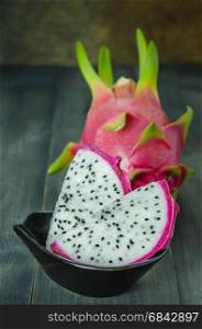 Ripe Dragon fruit with slice in bowl over wooden background , still life