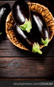 Ripe eggplant in a basket on the table. On a wooden background. High quality photo. Ripe eggplant in a basket on the table. 