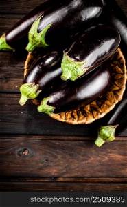 Ripe eggplant in a basket on the table. On a wooden background. High quality photo. Ripe eggplant in a basket on the table. 