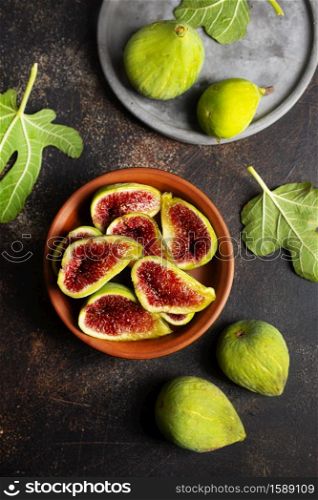 Ripe fig fruits with fig leaves on the brown background