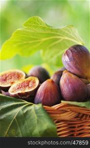 ripe figs with leaves in wooden basket