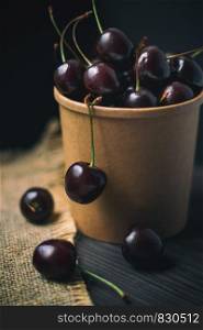 Ripe fresh sweet cherry in a cup on a dark background. Ripe sweet cherry in a cup on a dark background