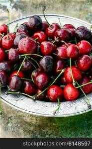 Ripe fruit of sweet cherry in the iron plate on metal background. Harvest rustic cherry