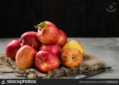 Ripe garden apples lined with burlap on a wooden background. Close-up, selective focus with copy space. Red ripe local apples
