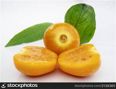 ripe golden berries, one cut in half and one whole accompanied by a mint leaf, on a white background Macro shot.