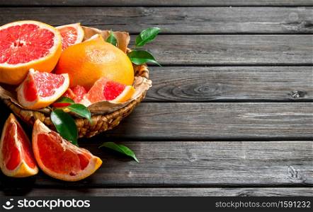 Ripe grapefruit in the basket. On black wooden background. Ripe grapefruit in the basket.
