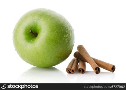 Ripe green apple with cinnamon sticks over reflective white background