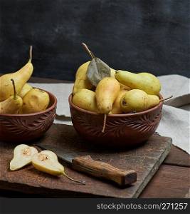 ripe green pears in a brown clay bowl on a table,  close up