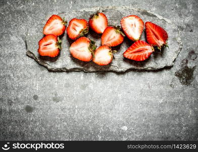 Ripe halved strawberries. On the stone table.. Ripe halved strawberries.