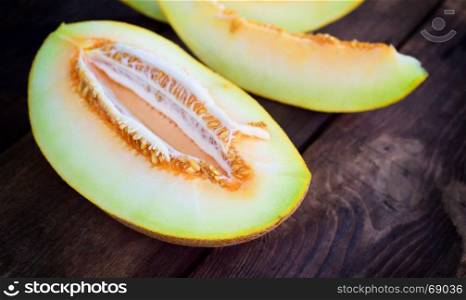 Ripe juicy melon cut in half on a brown wooden background, close up