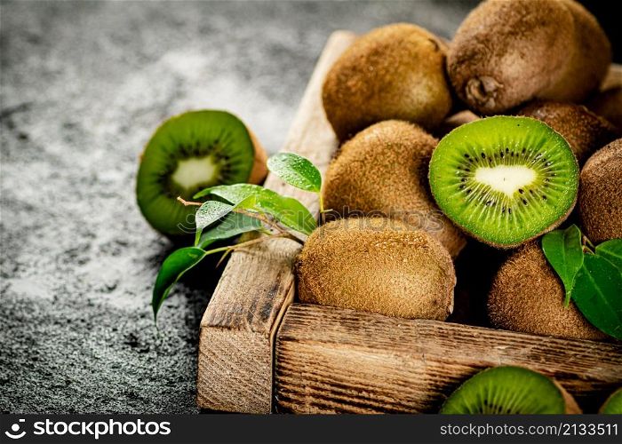 Ripe kiwi with leaves on a wooden tray. On a black background. High quality photo. Ripe kiwi with leaves on a wooden tray.