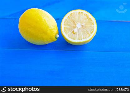 Ripe lemons and limes on blue wooden background.
