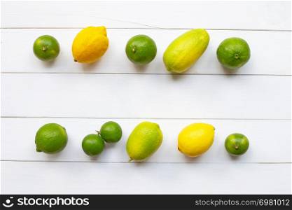 Ripe lemons and limes on white wooden background.