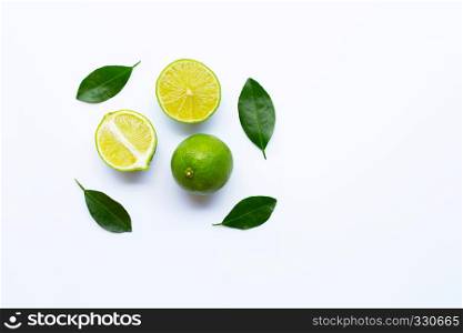 Ripe limes with green leaves on white background.