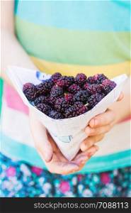ripe mulberry in the hands of a girl. bright tasty summer
