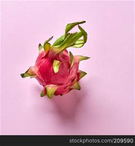 Ripe natural organic exotic fruit- dragon fruit on a pink background, place for text. Top view. Helthy vegan concept.. View from above to tropical fruit - pitahaya with green leaf on a pink background, copy space. Top view.