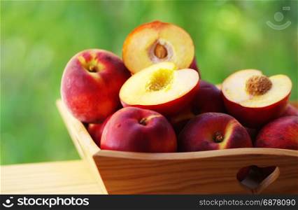 ripe nectarines and peaches on wooden basket